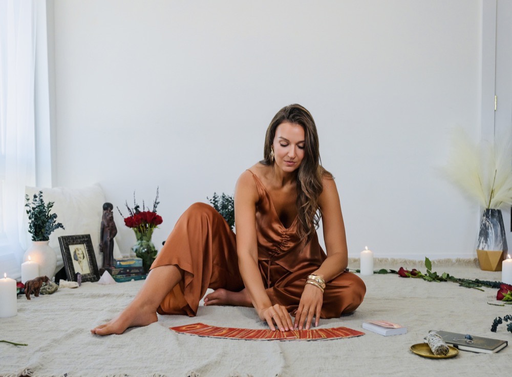 Rebecca seated with oracle cards, candles, roses and ancestral altar